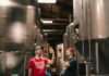 two men tasting beer near cylindrical tanks